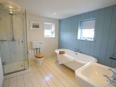A bathroom with a bathtub a shower toilet and sink at 1 South Cottages in Thorpeness