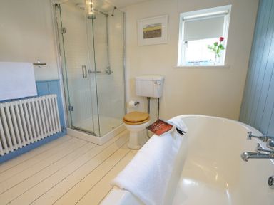A bathroom with a shower enclosure toilet bathtub and radiator at 1 South Cottages in Thorpeness