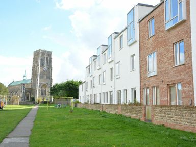 A row of townhouses with a playground and a church in the background at Parrotfish Bay Southwold