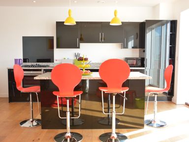 A kitchen with four red bar stools and black cabinets at Parrotfish Bay in Southwold