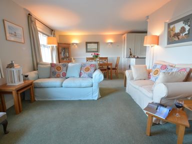 A living room with two sofas a dining table and chairs and side tables with lamps at Crabbe House in Aldeburgh