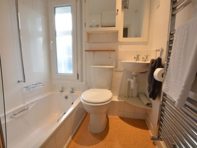 A bathroom with a bathtub toilet sink mirror and towel rack at Crabbe House in Aldeburgh