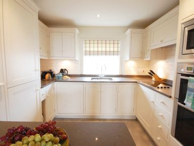 A kitchen with white cabinets sink and fruit bowl at Crabbe House in Aldeburgh