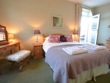 A bedroom with a bed with folded towels and pillows beside two bedside tables with lamps at Crabbe House in Aldeburgh