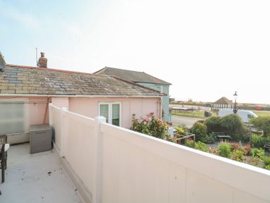 A balcony with white railing and a storage box overlooking a street and garden at Crabbe House in Aldeburgh