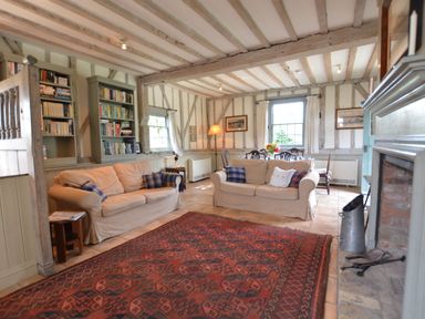 A living room with two beige sofas a red patterned rug built in bookshelves and a dining area at The Gig House Stowupland