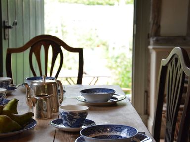 A dining table with blue and white china cups bowls plates a silver teapot and pears at The Gig House Stowupland