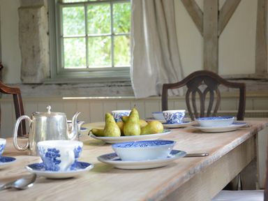 A wooden dining table with blue and white cups plates a silver teapot and a plate of pears at The Gig House Stowupland