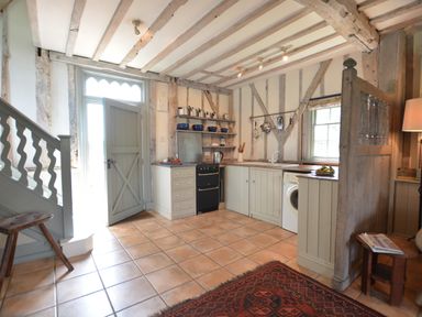 A kitchen with wooden beams a door a stove a washing machine and shelves at The Gig House Stowupland