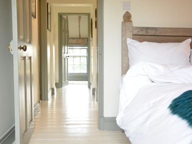A hallway with open doors leading to a window and part of a bed with white bedding at The Gig House in Stowupland