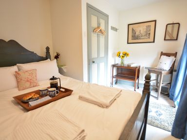 A bedroom with a wooden bed holding a tray with coffee and croissants at The Gig House Stowupland