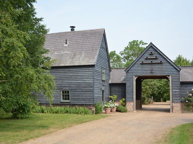 An outdoor scene with a grey wooden barn structure and a gravel path at The Gig House in Stowupland