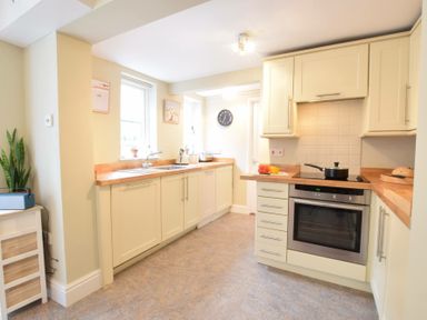A kitchen with cabinets a stove a sink and a clock on the wall at Spindrift Southwold