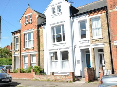 A row of attached houses with brick and white facades and parked cars on the street at Spindrift Southwold