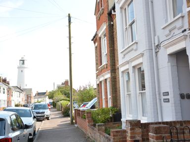 A street with parked cars and houses with a lighthouse in the background at Spindrift Southwold