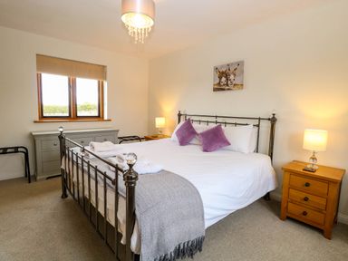 A bedroom with a bed, nightstand, and window at The Mulberry, nr Bungay