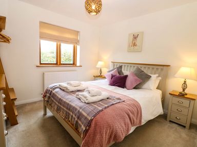 A bedroom with a bed and nightstand at The Mulberry, nr Bungay