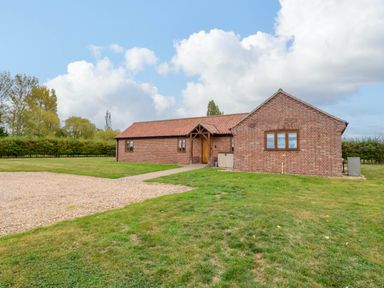 A brick house with a gravel pathway and garden area at The Mulberry, nr Bungay