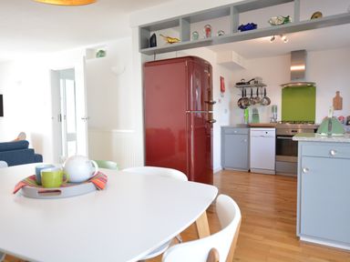 A kitchen with a red refrigerator gray cabinets and a white dining table with cups and a teapot at Aldeburgh Lodge Gardens in Aldeburgh