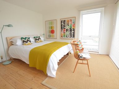 A bedroom with a bed a wooden bench and large windows at Aldeburgh Lodge Gardens in Aldeburgh