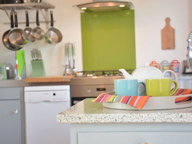 A kitchen counter with a tray holding a teapot and two cups with a colorful napkin at Aldeburgh Lodge Gardens Aldeburgh