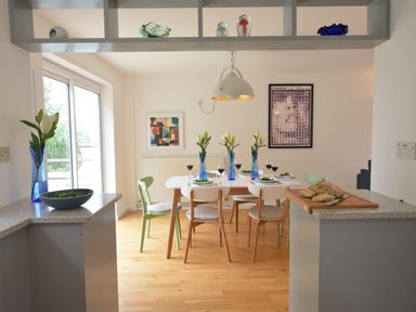 A dining room with a table set for six people including blue vases with flowers and glasses of wine at Aldeburgh Lodge Gardens Aldeburgh