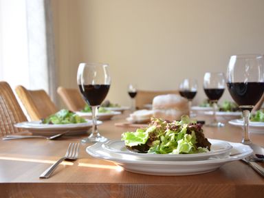 A dining table set with plates of salad, glasses of red wine, and a loaf of bread at Meadowsweet Blythburgh in Blythburgh near Reydon