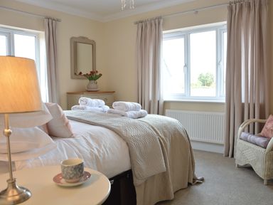 A bedroom with a double bed towels on the bed and a side table with a cup at Meadowsweet Blythburgh near Reydon
