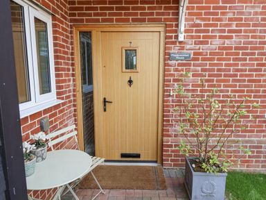 An entryway with a wooden door and a small table at Meadowsweet House Blythburgh near Reydon