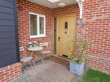 An entrance with a wooden door and a small table and chairs at Meadowsweet House Blythburgh near Reydon