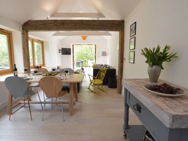 A dining area with a table set for four and a living room with a yellow rocking chair at Red Poll Barn Spexhall Near Halesworth