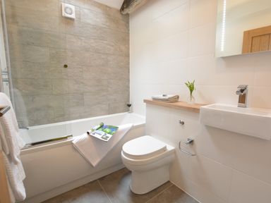 A bathroom with a bathtub a toilet sink mirror and towels at Red Poll Barn Spexhall Near Halesworth