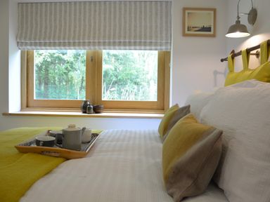 A bedroom with a bed featuring white bedding and yellow pillows near a window at Red Poll Barn Spexhall Near Halesworth