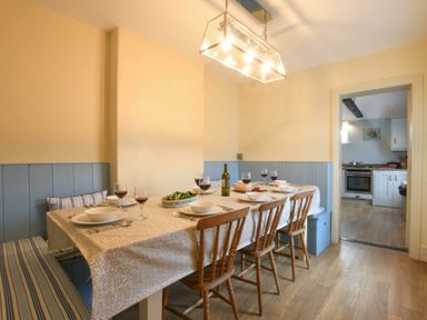 A dining room with a table set for six with wine glasses and bowls and wooden chairs at Walton House Southwold