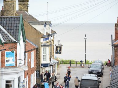 A street with brick and tiled roof buildings and people near the sea at Walton House Southwold
