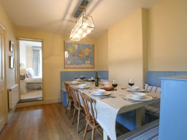 A dining room with a set table including wine glasses and a bottle of wine at Walton House Southwold