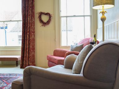 A sitting area with armchairs a floor lamp and a heart-shaped wall decoration at Walton House Southwold