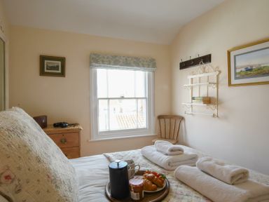 A bedroom with a bed holding folded towels and breakfast tray near a window at Walton House Southwold
