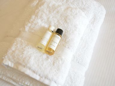 Two bottles of bath products on folded white towels at Walton House Southwold