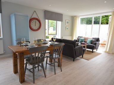A dining area with wooden table and chairs and a living room with sofas and a coffee table at Sweet Pea Southwold