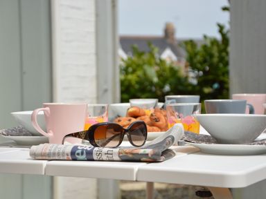 A table set with cups bowls glasses of orange juice a newspaper and sunglasses at Sweet Pea Southwold