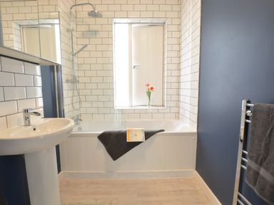 A bathroom with a bathtub shower sink and towel at Sweet Pea Southwold