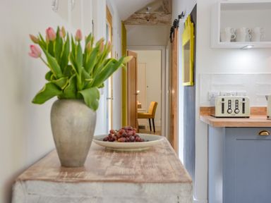 A kitchen counter with a toaster and a vase of pink tulips on a wooden table at Spexhall Barns in Halesworth