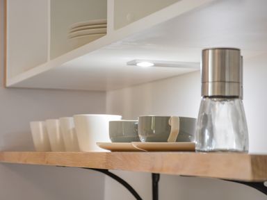 A kitchen shelf with cups saucers and a salt grinder at Spexhall Barns in Halesworth