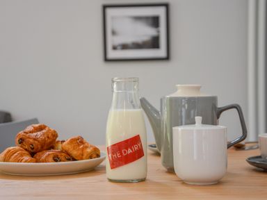 A table with croissants on a plate a bottle of milk a teapot and a sugar bowl at Spexhall Barns in Halesworth