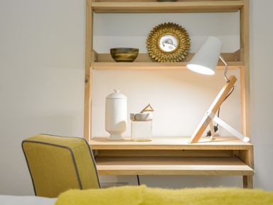 A wooden desk with a white lamp a white jar a glass container and a yellow chair at Spexhall Barns in Halesworth
