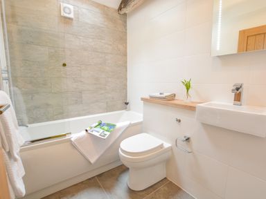 A bathroom with a bathtub shower toilet sink and towels at Spexhall Barns in Halesworth