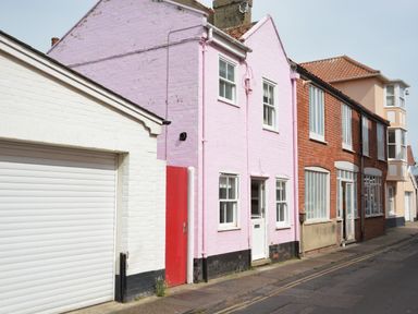 A street view showing houses with a pink house in the center and a white garage door to the left at Alinka Aldeburgh in Aldeburgh