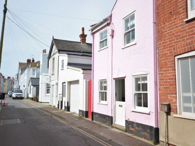 A street view with pastel colored houses and parked cars at Alinka Aldeburgh in Aldeburgh