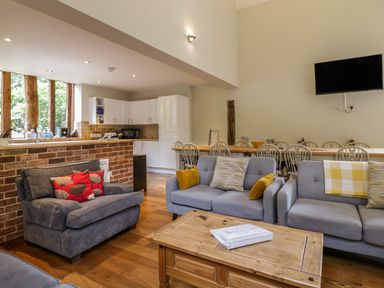 A living room with gray sofas and a wooden coffee table near a dining table and a kitchen at Quill Farm Barn in Campsea Ashe